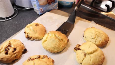 Slow-push-in-shot-of-a-baker-lifting-cooked-scones-onto-a-cooling-rack-with-a-utensil