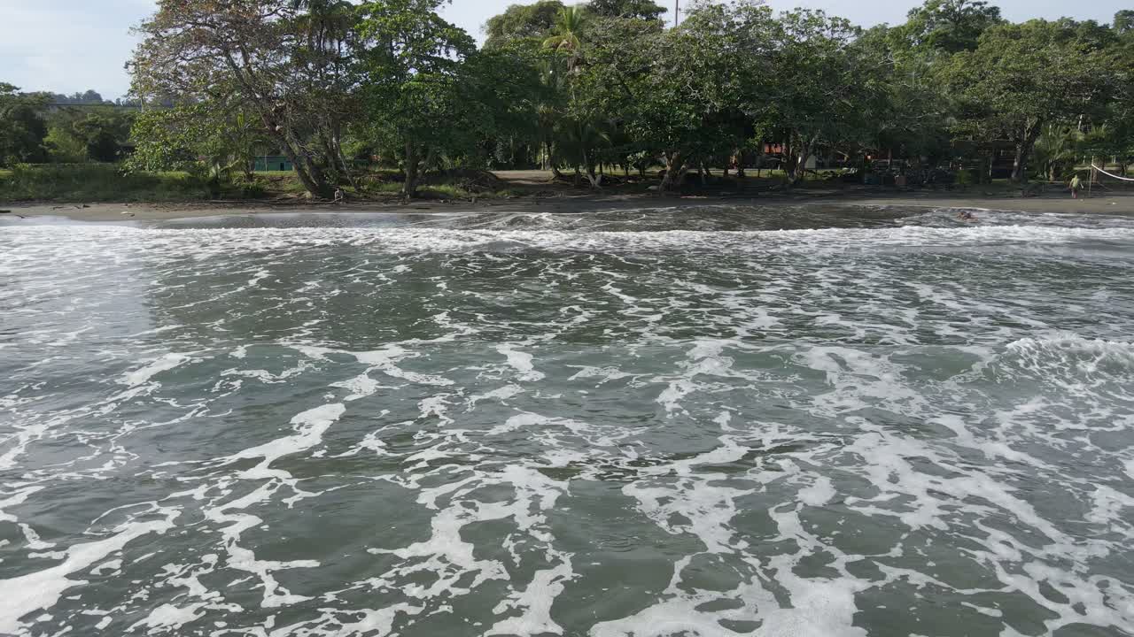 antena - las olas del océano chocan contra una playa boscosa con un cielo azul