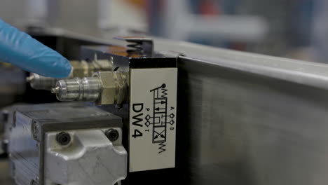 Close-up-shot-of-docent-with-gloves-teaching-students-machine-with-labal-in-hydraulic-lab