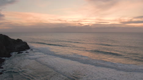 Volando-Sobre-El-Atardecer-Del-Océano-De-Invierno-Con-Olas-Rompiendo-Debajo