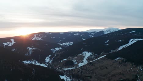 aerial view of the sun rising over snow capped mountains