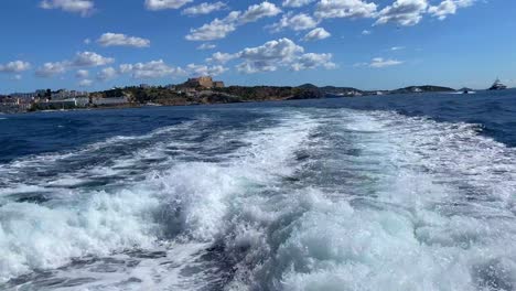 Blick-Auf-Die-Burg-Von-Ibiza-Von-Der-Schnellen-Kommerziellen-Bootsfahrt-Von-Ibiza-Zur-Insel-Formentera,-Boot,-Das-Sich-Bewegt-Und-Wellen-Erzeugt,-Segeln-Mit-öffentlichen-Verkehrsmitteln,-Spaßurlaub-Am-Mittelmeer,-Spanien,-4k-Aufnahme