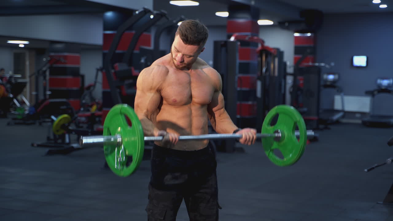 Handsome muscular man doing exercise with a heavy barbell. Athletic shirtless man training, Sportsman doing strength and endurance exercises with barbell. Workout in the gym.