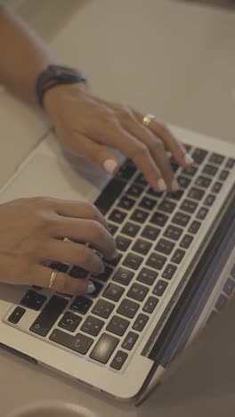 female hands typing on laptop at desk, close up view