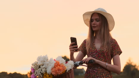 Ziemlich-Süßes-Mädchen,-Das-An-Einem-Sonnigen-Tag-Im-Park-Mit-Palmen-Neben-Ihrem-Fahrrad-Ein-Smartphone-Benutzt.-Hübsches-Mädchen,-Das-An-Einem-Sonnigen-Tag-Im-Park-Neben-Ihrem-Fahrrad-Ein-Smartphone-Benutzt.