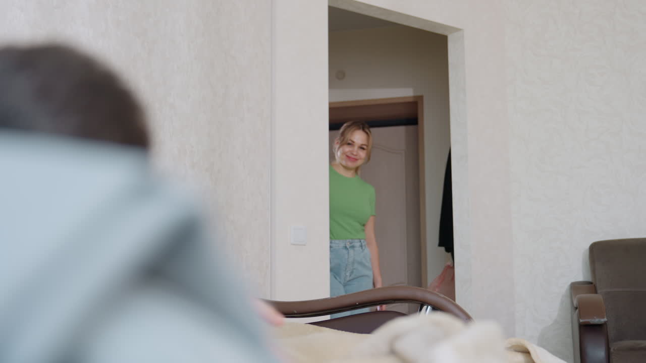 Close up of kid stretching on bed under blanket as mother in green top enters room smiling to check on him creating tender family atmosphere of love care comfort warmth and nurturing