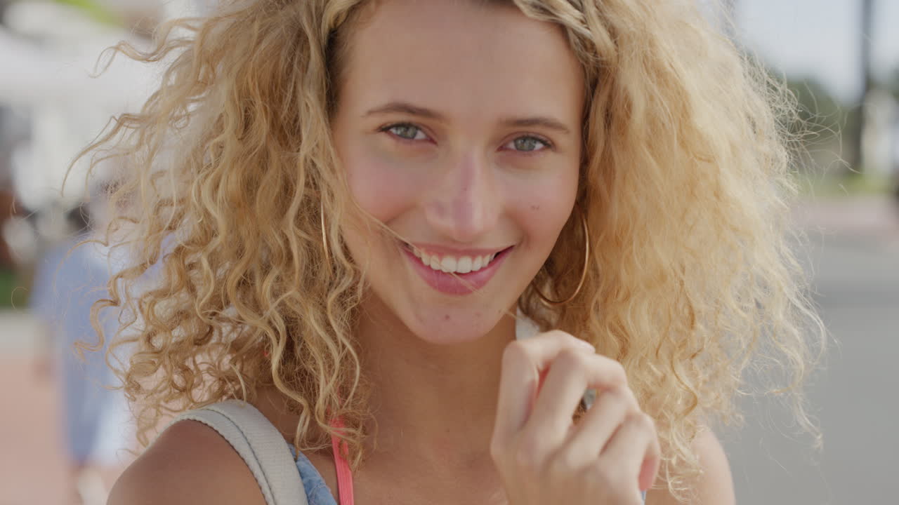 ritratto ravvicinato di una bellissima donna bionda che corre con la mano tra i capelli sorridendo sicura di sé godendo di una giornata di sole rilassata in vacanza estiva