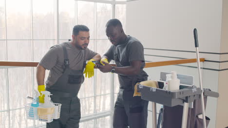 and arabic cleaning men looking at smartphone near a cart cleaning 1