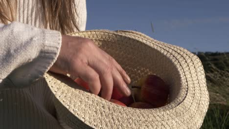 Mujer-Sosteniendo-Un-Montón-De-Manzanas-Rojas-Con-Un-Sombrero-De-Paja-De-Plano-Medio