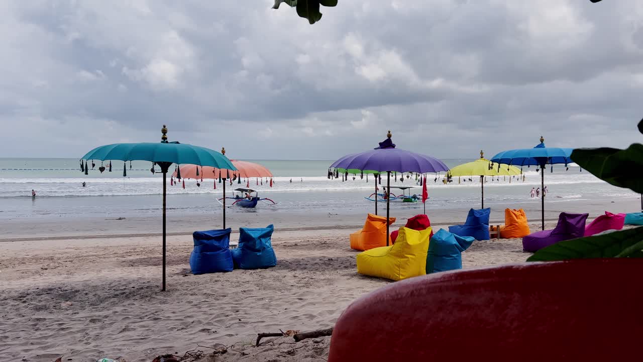 Colorful umbrellas line the sandy shores of Kuta Beach, Bali, while fishing boats rest at the water’s edge, offering a vibrant scene of island culture, travel, and tropical serenity