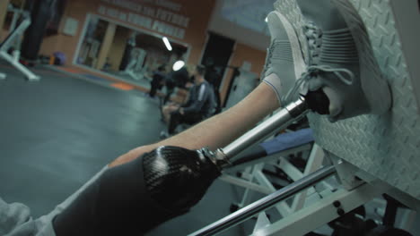 tracking shot of motivated athlete with prosthetic leg training on leg press machine in modern gym. adult sporty man with artificial limb does strength workout using professional sports equipment.