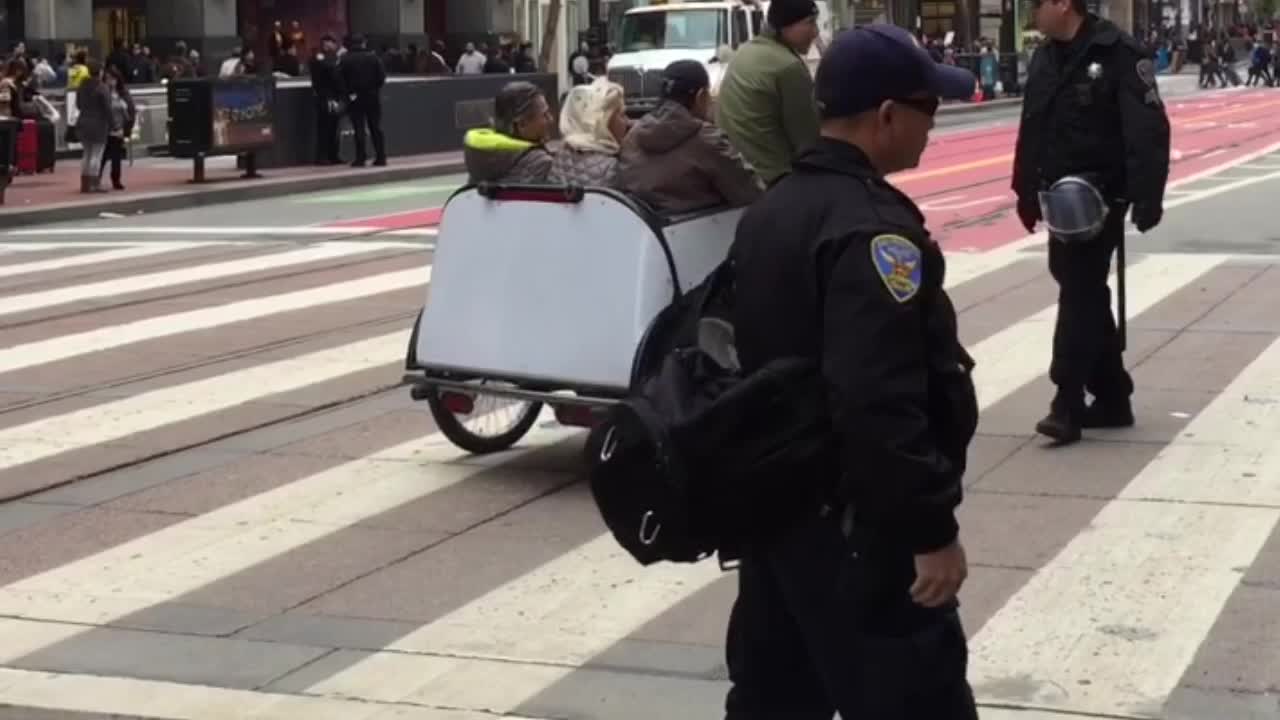 Cop stops three tourists riding in a pedicab on Market Street just before the Women's Rights March in protest against the election of Donald Trump