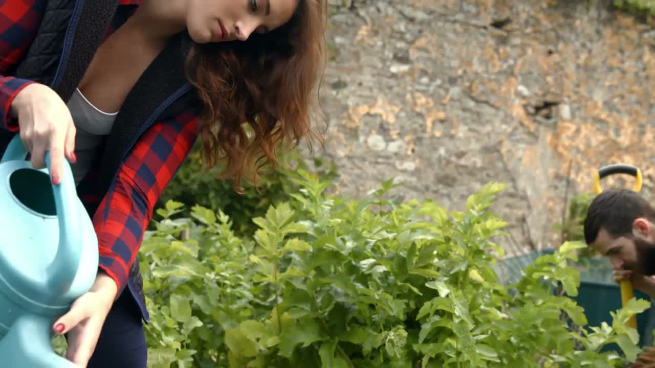 mujer joven regando las plantas bastante