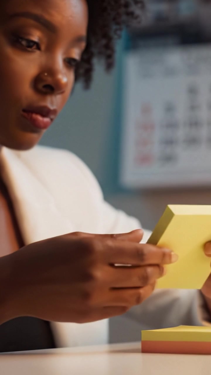 Focused Individual Engaging with Colorful Sticky Notes in a Bright Office Setting, Demonstrating Creativity and Attention to Detail in Their Task.