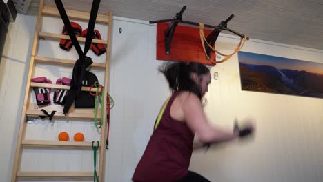 foto estática del perfil de la parte superior del cuerpo de una mujer haciendo sentadillas con saltos en un pequeño gimnasio - figura de entrenamiento matutino intensivo