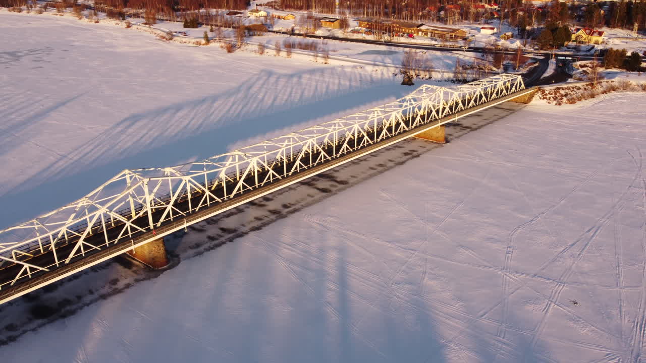 Aerial following snowy bridge over frozen river, Tornio, Finland