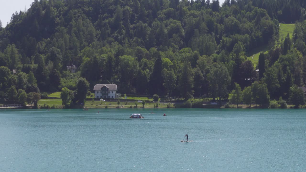 un solitario stand-up-paddle-boarder remando en el lago bled, eslovenia