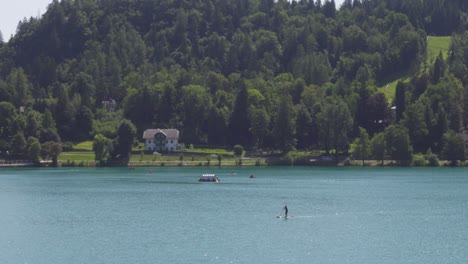 a lone stand-up-paddle-boarder paddling in lake bled, slovenia