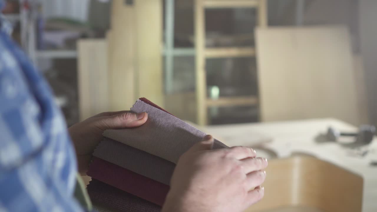 muestras de tela de color para la fabricación de muebles en las manos de los hombres kraftman de cerca