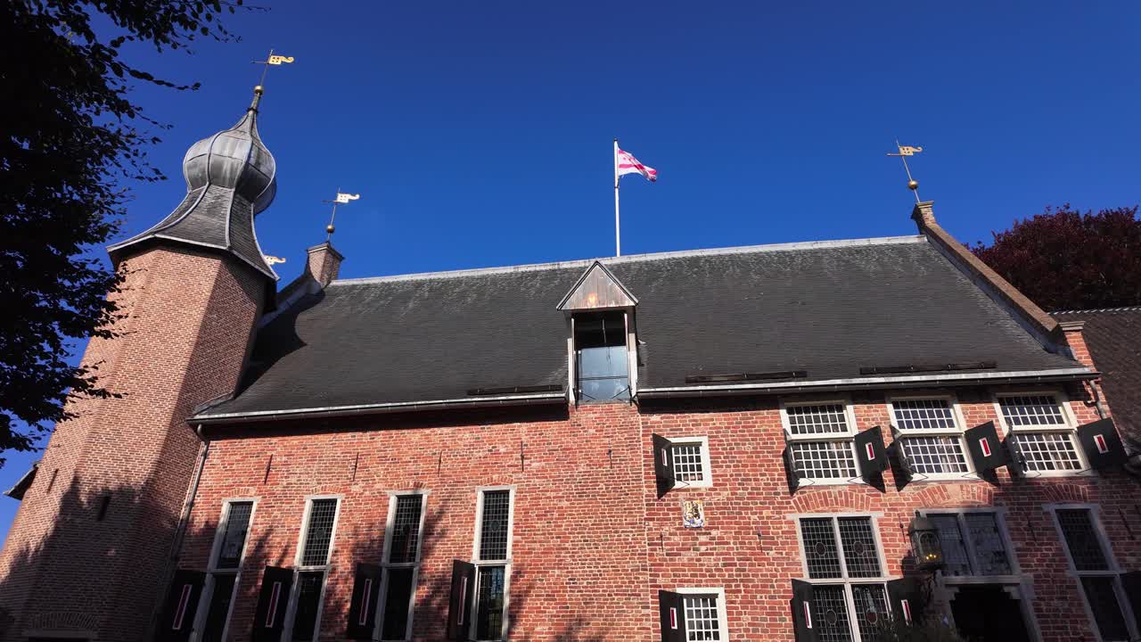 Detailed view of a historic brick castle tower with weather vanes and Drenthe flag under bright blue sky in Coevorden, Drenthe, Netherlands | Coevorden, Drenthe, Nederland