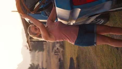 retrato de video vertical de una mujer descargando mochilas de un camión de recoger en un viaje por carretera al campo