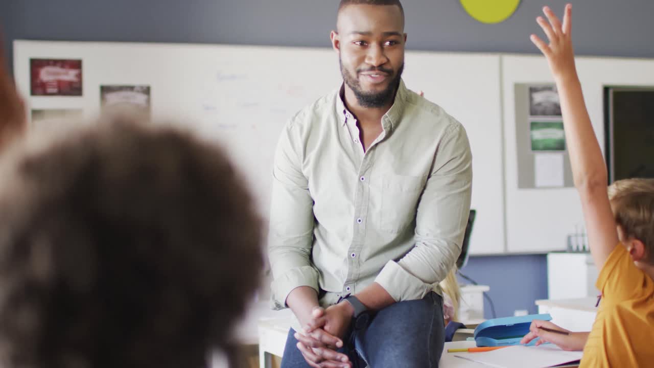 Video of happy african american male teacher during lesson with class of diverse pupils
