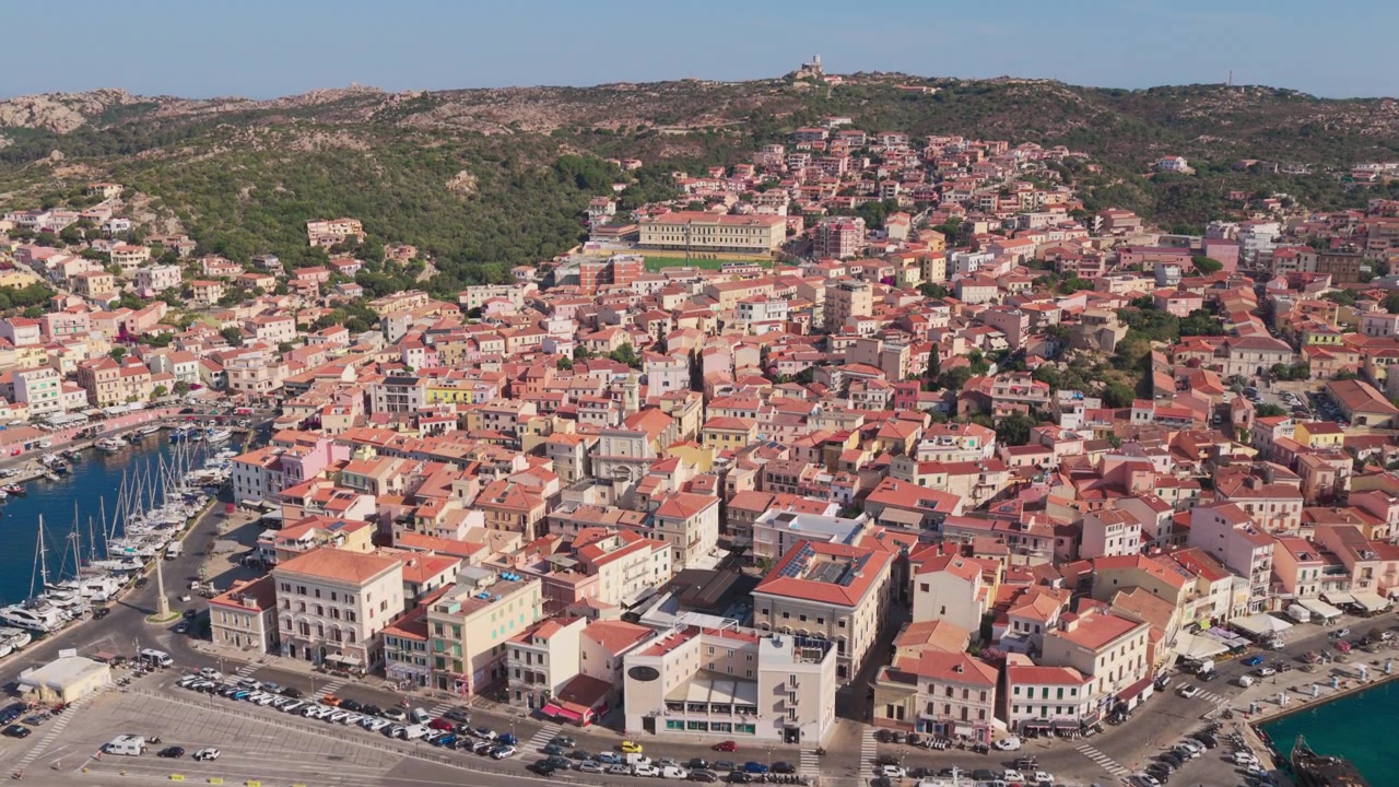 Ampia ripresa aerea in ascesa sulla città vecchia e sul porto de La Maddalena, una popolare destinazione per la vela e i viaggi, rinomata per i suoi panorami mozzafiato, la storia e il paesaggio costiero mediterraneo in Sardegna, Italia.