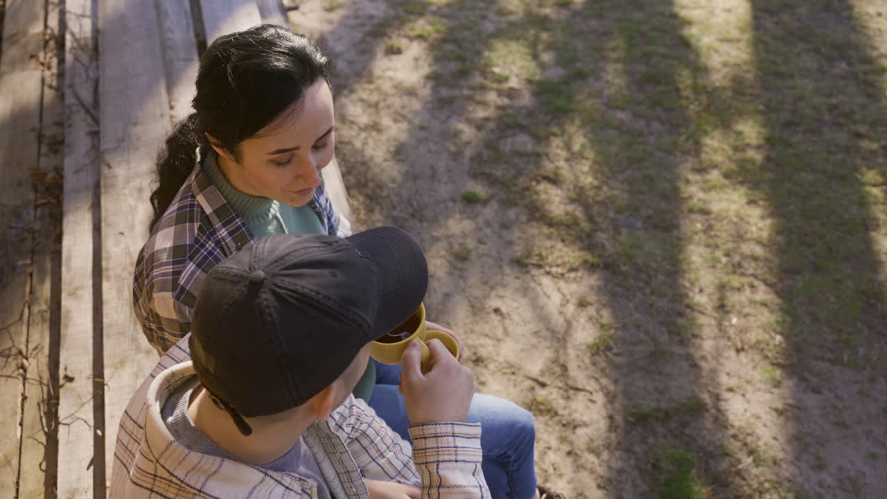 vista superior de una pareja caucásica hablando mientras beben té fuera de una casa de campo