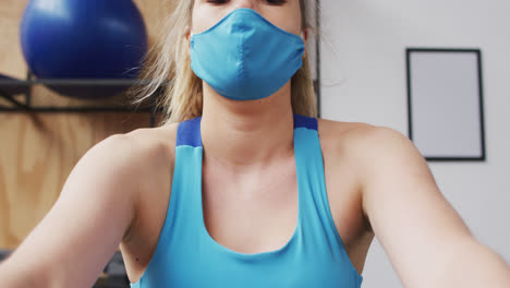 caucasian woman wearing face mask exercising at gym