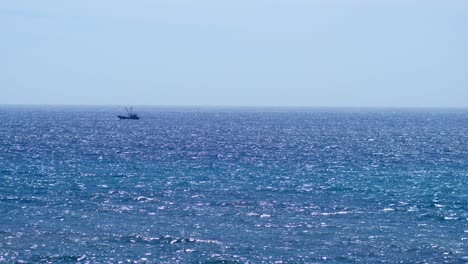 Small-fishing-boat-sailing-through-waves-on-horizon