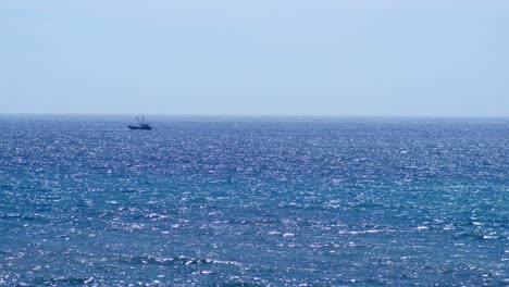 small fishing boat sailing through waves on horizon