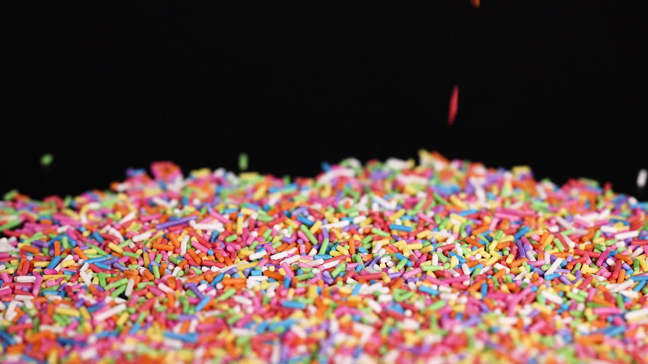 Vibrant sprinkles cascade onto a pile