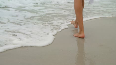 sección baja de la mujer caminando descalza en la playa 4k