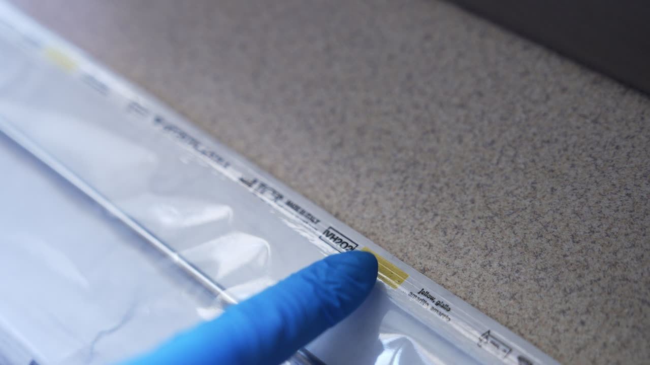 Medical tool for surgery in transparent plastic bag. Gloved medic's hand checks the bag with finger. Preparation for sterilization instruments in clinics.