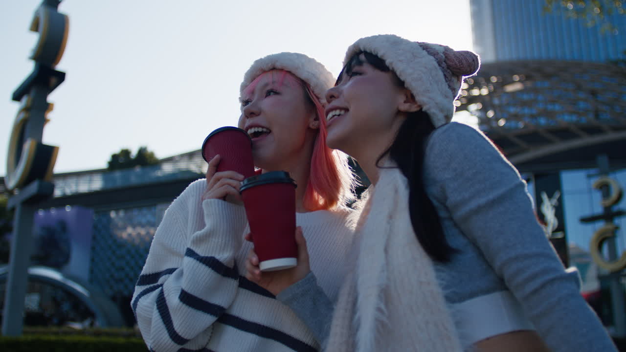 Two women in an urban environment holding coffee cups