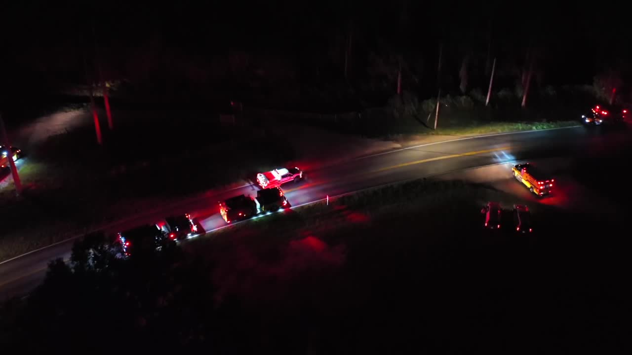 Aerial view of emergency vehicles with flashing lights responding to an incident on a dark rural road in America, creating a dramatic scene filled with urgency and tension. Top down. PA, USA.
