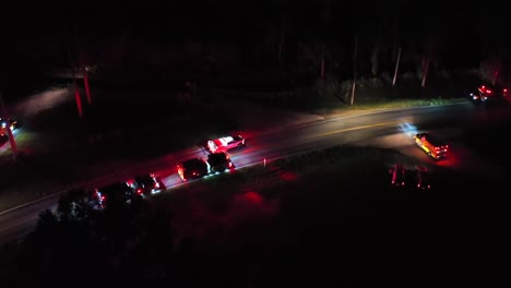 aerial view of emergency vehicles with flashing lights responding to an incident on a dark rural road in america, creating a dramatic scene filled with urgency and tension. top down. pa, usa.