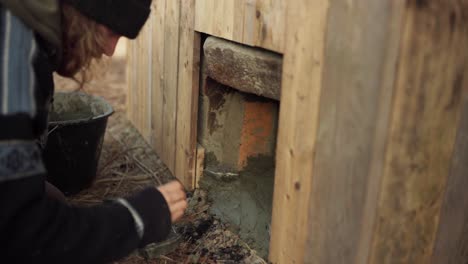 the man is applying cement to the stove beneath the diy hot tub - timelapse