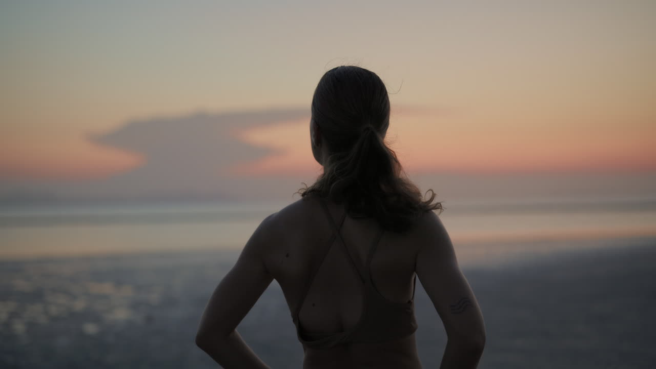 Woman Standing on Beach Looking at Sunset Horizon