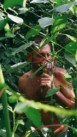 man smelling flowers in a forest