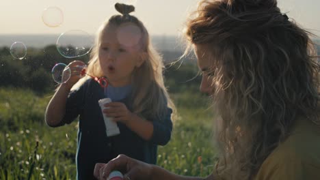 Kleines-Kaukasisches-Mädchen-Mit-Mutter,-Die-Mit-Blasen-Spielt.