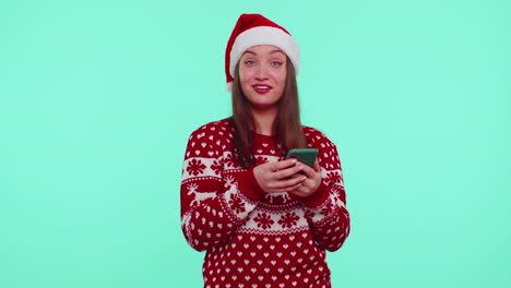 Erwachsenes-Teenager-Mädchen-Im-Weihnachtspullover-Schaut-Auf-Smartphone-Display-Und-Freut-Sich-Aufrichtig-über-Erfolg-Und-Glück