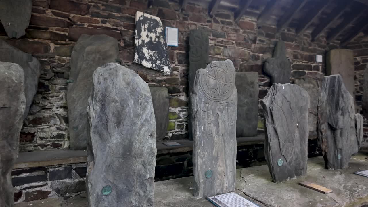Ancient stone crosses arranged in a rustic gallery, showcasing Isle of Man heritage and history