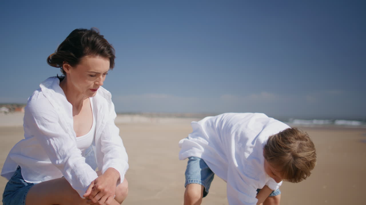 Mother boy playing sand at windy sunny beach closeup. Carefree woman talking son