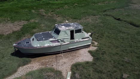 Abandoned-old-fishing-boat-carcass-shipwreck-in-shipyard-low-tide-mud-flats-graveyard-orbit-right