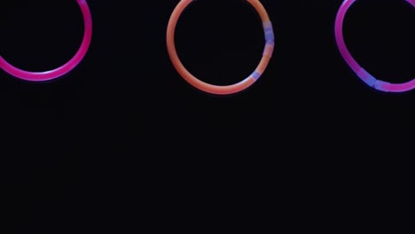 animation of colorful neon glow sticks over black background with copy space