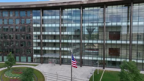 American-flag-waving-in-front-of-glass-USA-government-building-in-urban-America