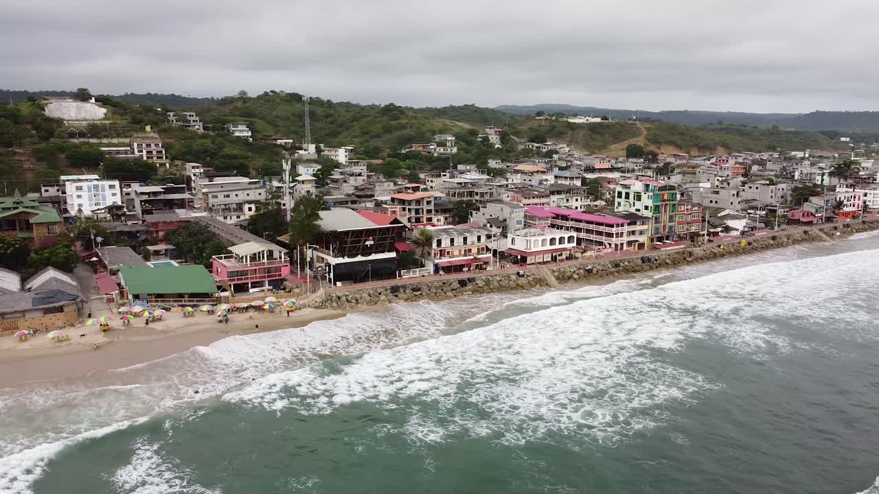Aerial orbit at high tide in Montanita Ecuador beach town. Surfing towns in Ecuador. Vacation beach destinations.
