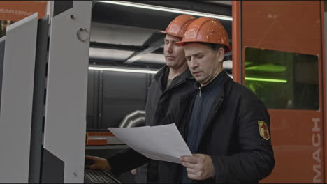 factory workers inspecting machine with blueprint