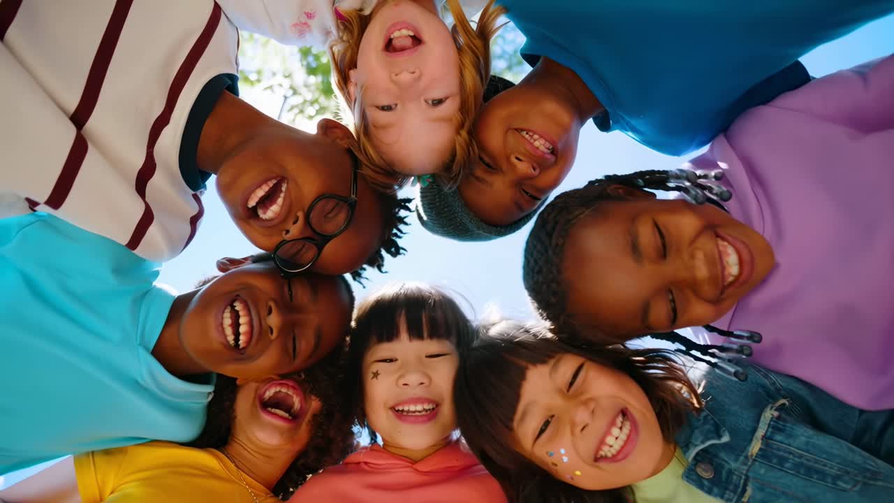 A joyful, low-angle video shot of diverse kids in a circle, smiling under a sunny sky